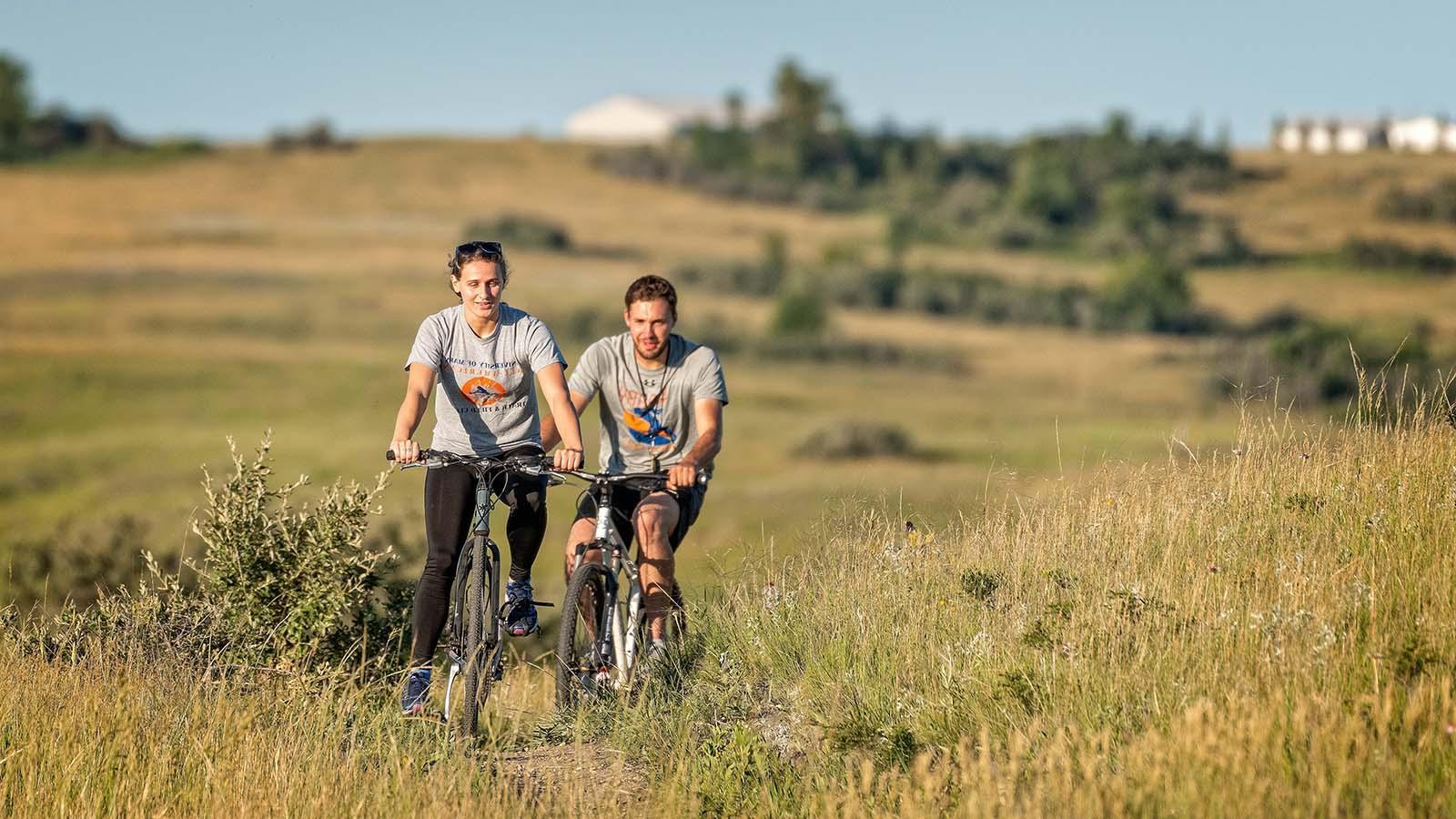 Couple riding mountain bikes on trail in countryside